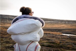 With her baby Dolly snug in her amauti, Aleashia Echalook stands outside her home looking toward the Innuksuak river. As the youngest board member of Pituvik Landholding Corporation, the mother of three is hopeful about what the new hydro project will bring for the next generation.