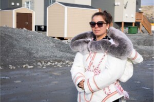 Aleashia Echalook, mother of three and the youngest board member of the Pituvik Landholding Corporation, carries her three-month-old baby, Dolly, in her amauti as she walks through Inukjuak. She reflects on how the Innavik Hydro project will create opportunities for future generations in her community.