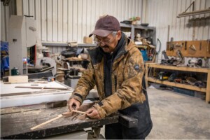Charlie Elijassiapik, a hunter and member of the Unaaq Men’s Association in
Inukjuak, builds a miniature sled at the association’s wood workshop. Unaaq creates opportunities for elders to share traditional hunting skills and tool-making knowledge with youth in Inukjuak—and is one of many programs the community plans to support with Innavik Hydro revenues.