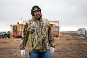 Eric Atagotaaluk reflects as he walks on the land outside his cabin near the Arctic village of Inukjuak in northern Quebec. As project director of Pituvik Sarvaq Energie, he says there were times over the years when it was unclear if the Innavik project would move forward. Now completed and operational as of winter 2024, Innavik has become a source of pride for the community.