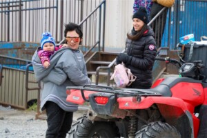 A woman carries her baby in an amauti outside the Northern Store in
Inukjuak, October 2024. The traditional Inuit parka features a built-in pouch below the hood that can hold babies until about age two.