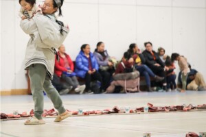 An Inuk woman carries her baby at a community feast in Inukjuak, October 2024. The gathering at Pinguavik Recreation Centre features
traditional country foods including caribou and whale. Climate change is making it harder and more dangerous to hunt as ice becomes less stable and animals change their migration routes.